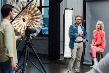 Yakışıklı sanat yönetmeninin seçici odağı. Cebinde çekici bir modelin yanında duruyor ve fotoğrafçıya bakıyor. 