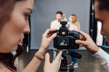 Resim yönetmeni ve fotoğrafçı yakınlarındaki yakışıklı modelin fotoğrafıyla dijital kameranın seçici odağı. 
