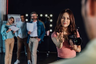 Fotoğraf stüdyosundaki modele bakarken mutlu fotoğrafçı hareketlerinin seçici odağı 