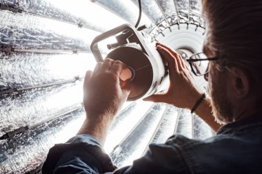 selective focus of bearded art director touching reflector in photo studio  clipart