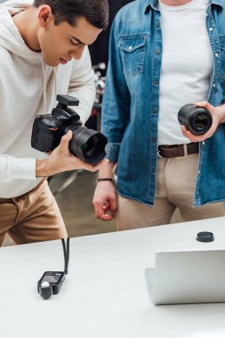 Sanat yönetmeninin yakışıklı fotoğrafçının yanında fotoğraf lensi tutarken çekilmiş görüntüsü. 