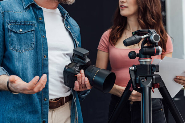 cropped view of creative director standing with photographer near tripod 