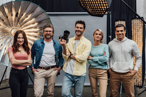 веселая команда улыбается, глядя на камеру в фотостудии
 