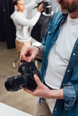 Dijital kamera tutan sakallı fotoğrafçı görüntüsü. 