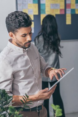 İş kadınının yanında dijital tablet kullanan karışık ırk kargaşası ustasının seçici odağı 