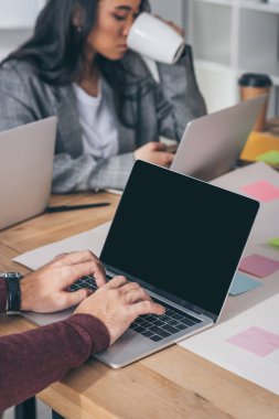 İş kadını çay içerken laptopta boş ekranla yazı yazarken görüntülenmiş. 