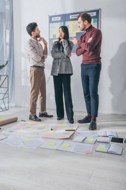multicultural scrum masters standing and talking near sticky notes on floor  clipart
