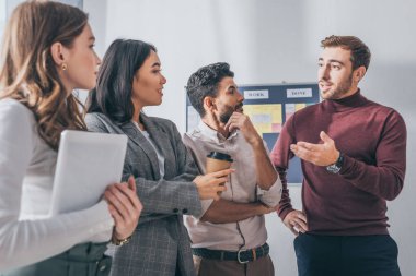 selective focus of handsome scrum master gesturing near multicultural coworkers  clipart