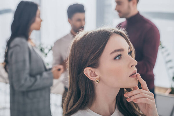 selective focus of pensive scrum master touching lips near coworkers 