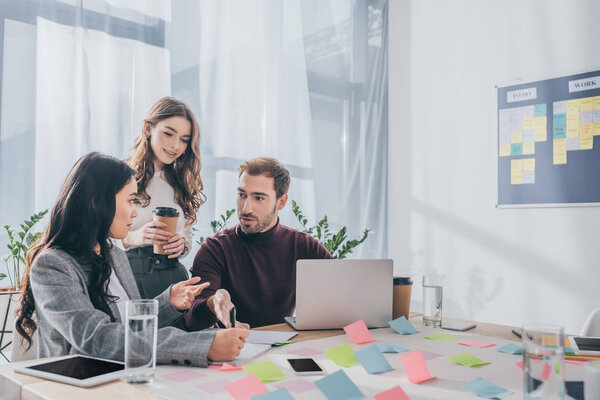 бизнесмен рядом с мультикультурной бизнесвумен в офисе
 