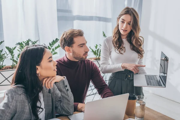 Atractiva Mujer Negocios Señalando Con Dedo Computadora Portátil Cerca Compañeros — Foto de Stock