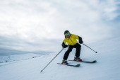 Sportler hält Skistöcke beim Skifahren auf weißem Schnee