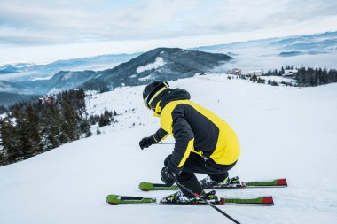 sportsman in helmet skiing in mountains clipart