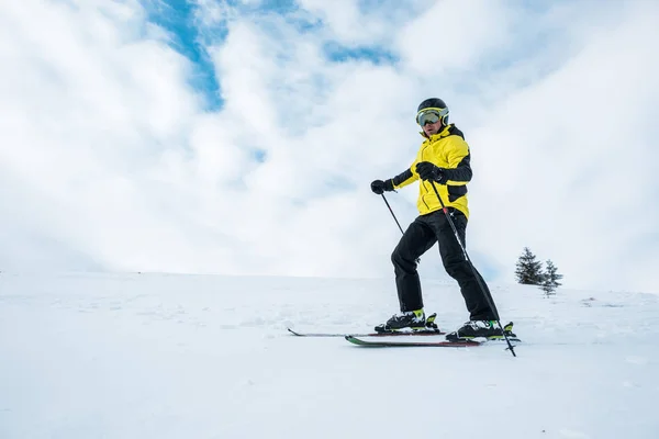 Kışın yamaçta kayak yapan kasklı ve gözlüklü bir sporcu. — Stok fotoğraf