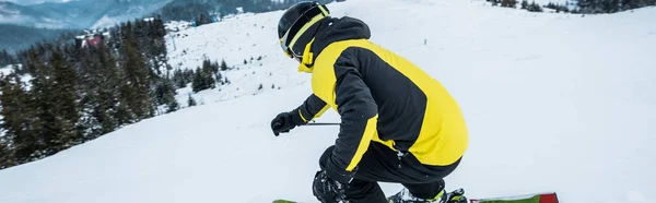 Panoramic shot of sportsman in helmet skiing in wintertime — Stock Photo, Image