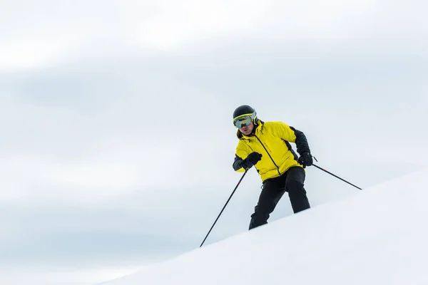 Sciatore in casco reggendo bastoni e sciando in pista in inverno — Foto Stock