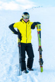 lyžař v helmě stojící u lyžařských holí na sněhu