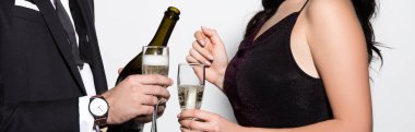 Beyaz panoramik karede sevgililer günü için ellerinde şampanya şişesi ve gözlük olan çiftin kırpılmış görüntüsü. 