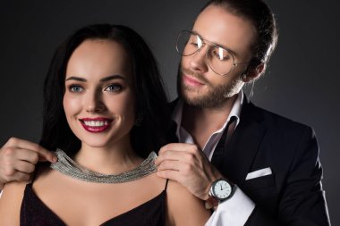 Sevgililer Günü 'nde gülümseyen kız arkadaşının kolyesini takan bir adam.