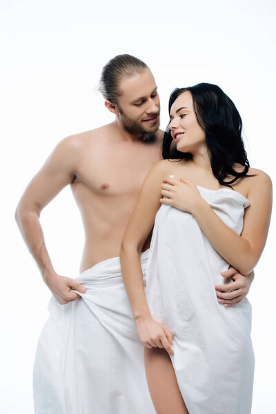 naked young couple hugging in white sheets, isolated on white