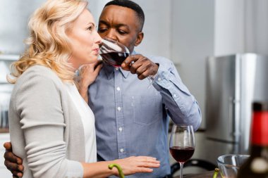 Seçici odak noktası, Afrika kökenli Amerikalı bir adamın mutfakta arkadaşına şarap kadehi vermesi. 