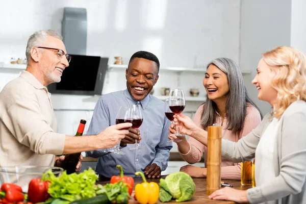 微笑的多文化朋友在厨房里与酒杯叮当作响 — 图库照片