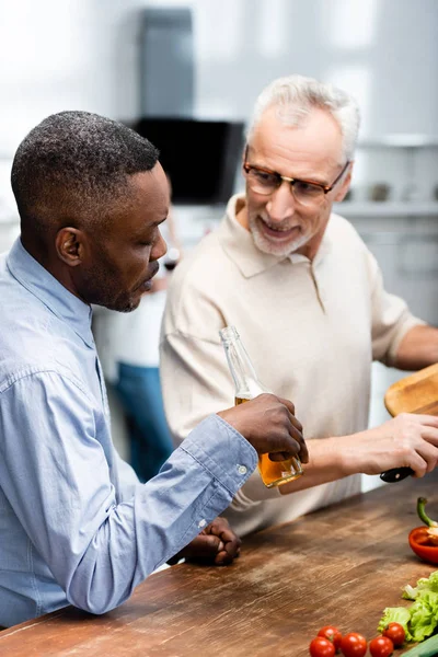 African American Man Holding Beer His Smiling Friend Cooking Kitchen — Stock Photo, Image