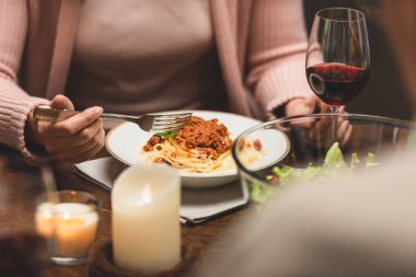 Yemek boyunca masada oturup makarna yiyen bir kadın görüntüsü. 