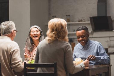 seçici odak noktası yemek sırasında arkadaşlarıyla konuşan çok kültürlü bir erkek ve kadın. 