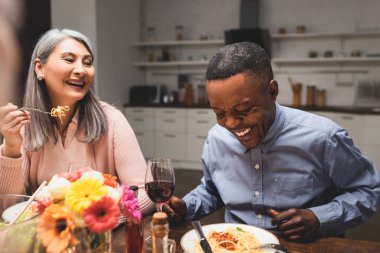 Afro-Amerikan erkek ve Asain kadın yemek boyunca gülümsüyor. 