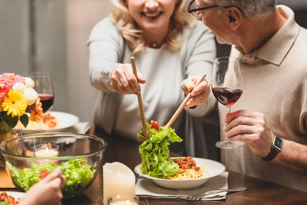 Vista Recortada Mujer Sonriente Poniendo Ensalada Plato Amigo Durante Cena — Foto de Stock