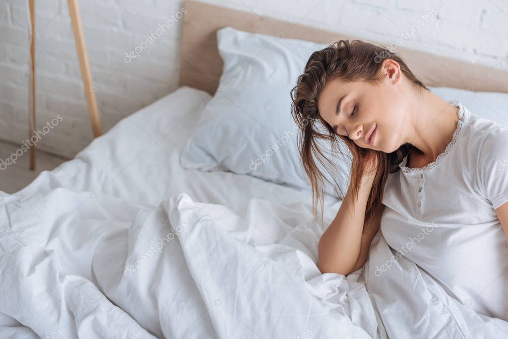 Dreamy woman with closed eyes resting in bed