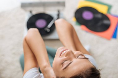 Vinil plakların yanında gülümseyen mutlu kızın seçici odağı 