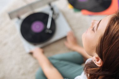 Seçici odak noktası, rüya gibi bir kızın klasik kayıt cihazının yanında müzik dinlemesi. 