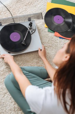 selective focus of vintage record player near girl sitting on carpet  clipart