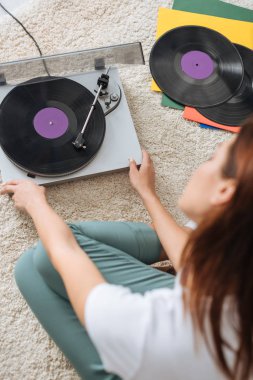 selective focus of vintage record player near girl sitting on carpet  clipart