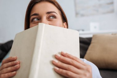 Yüzü kitapla kaplı rüya gibi bir kızın seçici odak noktası. 