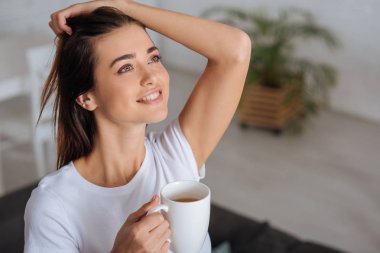 attractive woman dreaming while holding cup of tea 