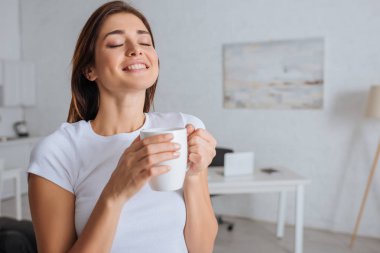 cheerful woman dreaming while holding cup of tea  clipart