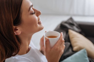 side view of attractive woman holding cup with tea  clipart