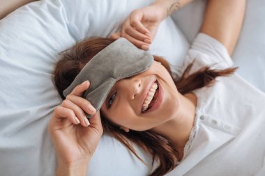 overhead view of happy young woman in eye mask resting in bedroom  clipart