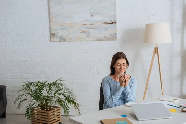 Joven Mujer Ensueño Sosteniendo Taza Sonriendo Cerca Mesa Casa — Foto de Stock