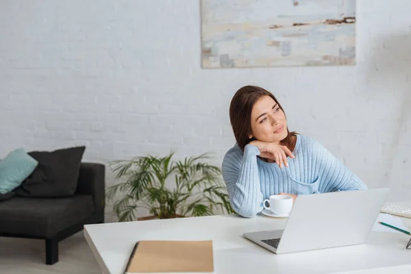 Verträumte Frau Schaut Bei Laptop Und Tasse Auf Tisch Weg — Stockfoto