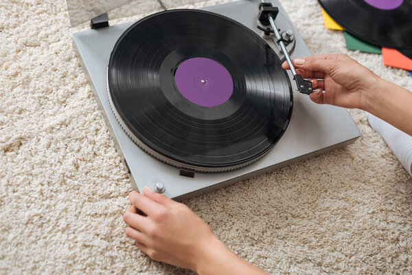 cropped view of young woman touching retro record player 