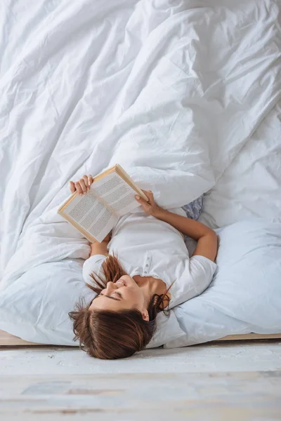 Vista Superior Livro Leitura Menina Sorridente Enquanto Refrigerando Cama — Fotografia de Stock