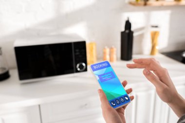 cropped view of woman holding smartphone with booking app 