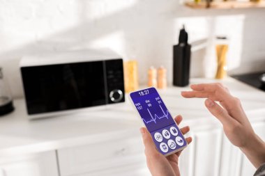 cropped view of woman holding smartphone with health app 