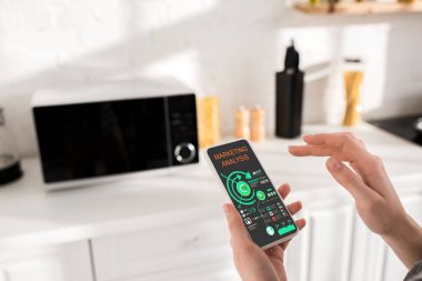 cropped view of woman holding smartphone with marketing analysis app 