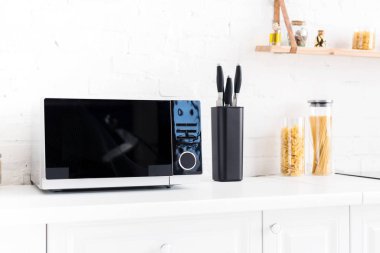 microwave, pasta and knives on surface in kitchen 