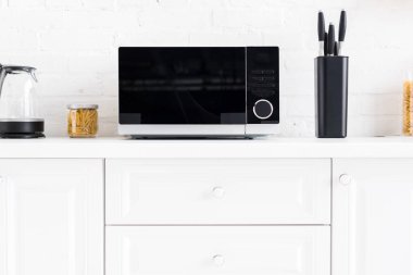 microwave, electric kettle, pasta, knives on surface in kitchen 